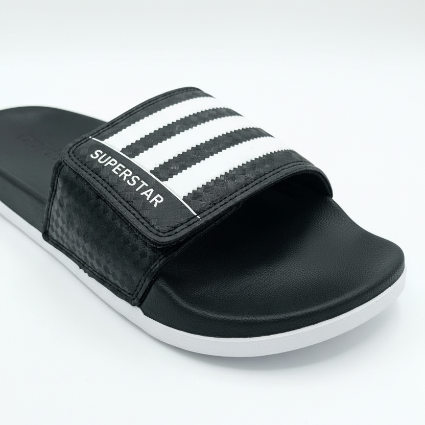 Adidas Superstar slide negra vista detallada angular close-up sección blanca 3 rayas negras verticales serradas SUPERSTAR blanco izquierdo velcro checker negro footbed negro suela blanca