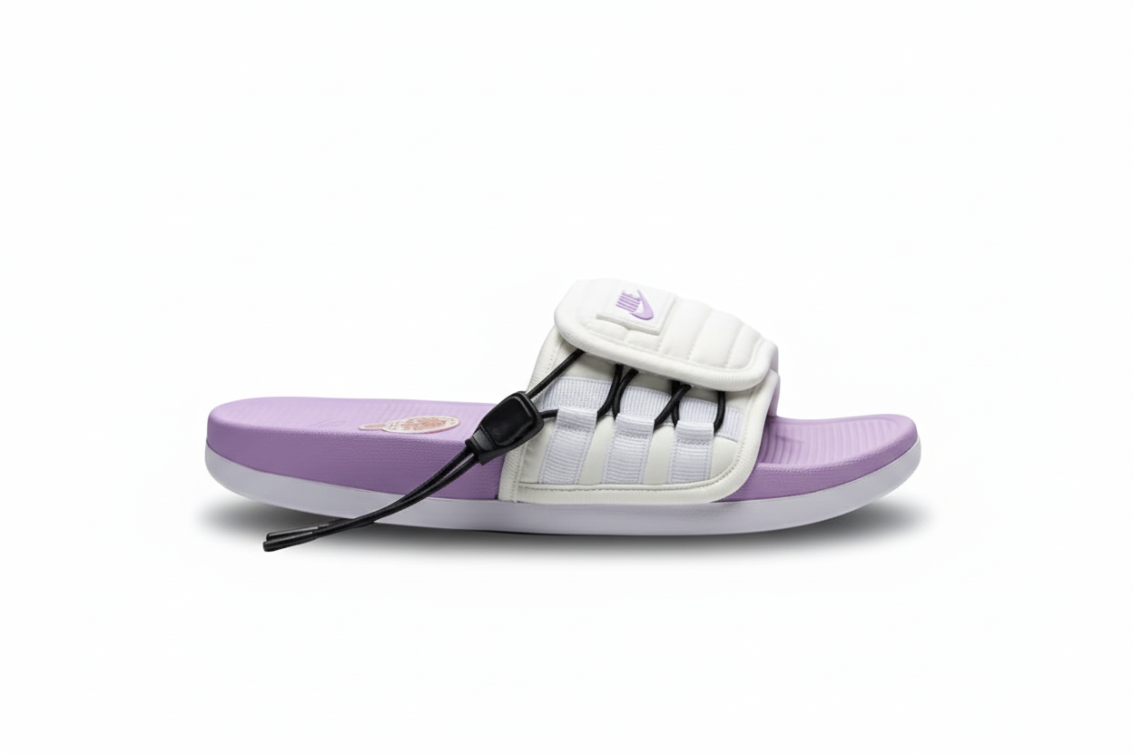 Nike slide crema morada vista lateral profesional correa puffer quilted cage bandas blancas horizontales tabs negros parche Nike swoosh morado superior cordón negro stopper derecho footbed morado lavanda emblema rojo dorado suela blanca