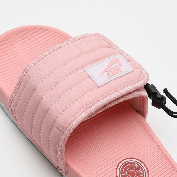 Nike slide rosa salmón vista detallada angular top-down diagonal superior-izquierda inferior-derecha correa puffer quilted velcro cierre izquierdo parche blanco Nike swoosh rosa centro-derecho clip negro J-hook derecho footbed rosa SOFT TRY emblema rosa oscuro NIKE swoosh relieve suela gris claro borde inferior-derecho